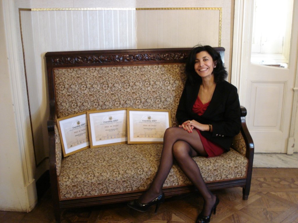 Norma beside three Cuyo Oliva 2007 award diplomas displayed on a sofa